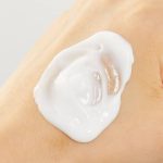 Close-up of a dollop of thick, white cream on the back of a hand or arm.